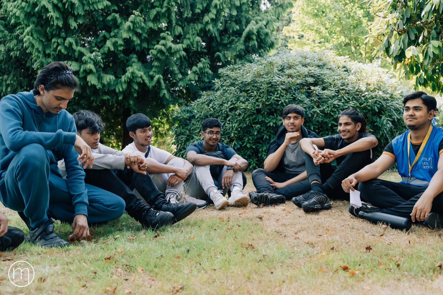 A group of Summer Camp participants sitting together on the grass outdoors