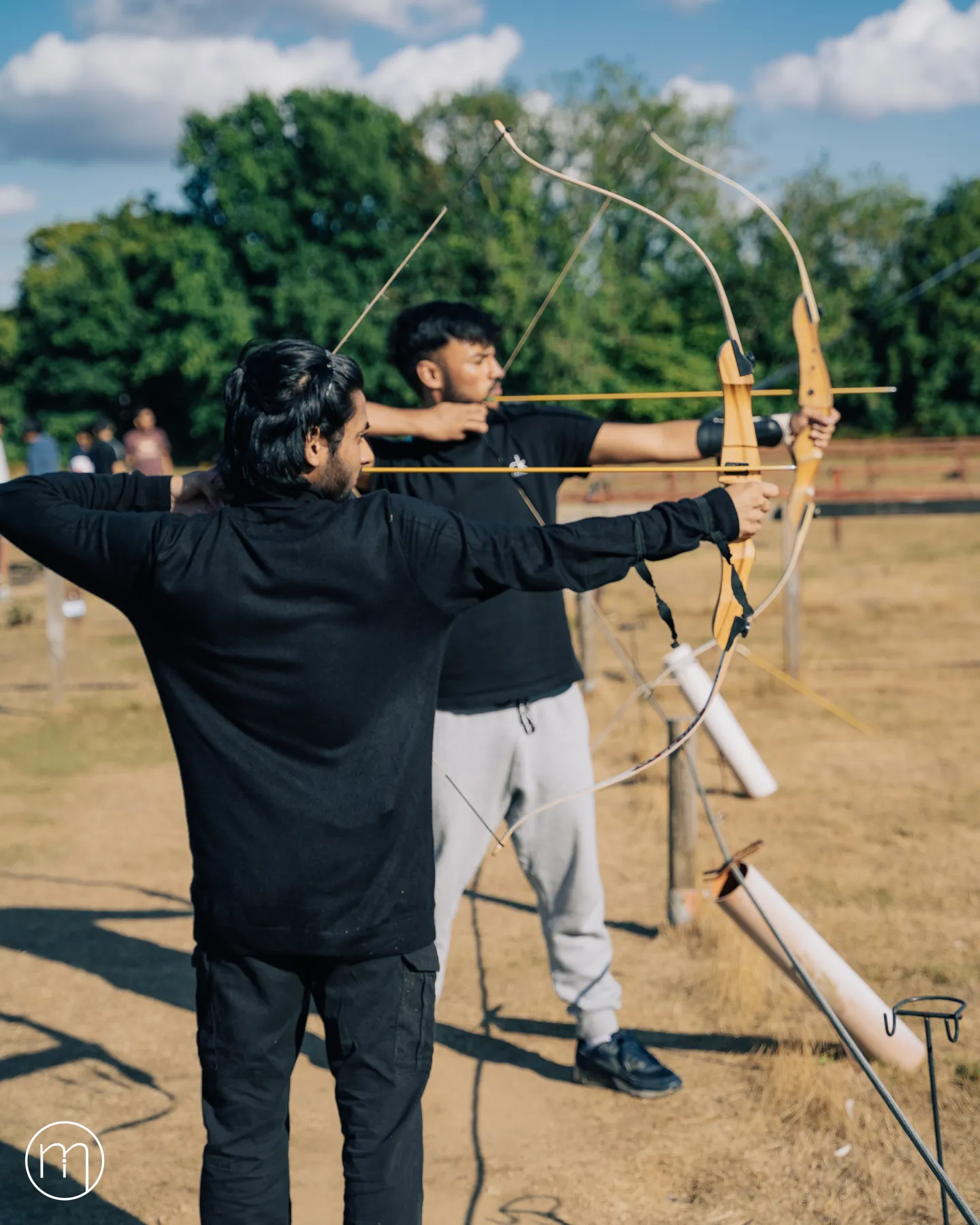 Two Summer Camp participants drawing their bows during an archery session